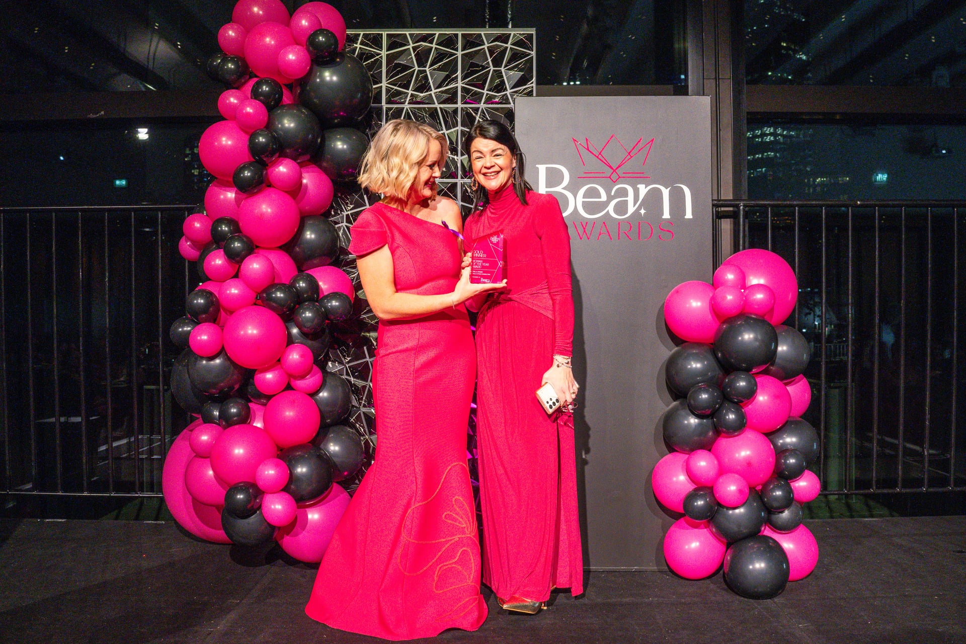 Two Beam Awards winners celebrating on stage with their trophy